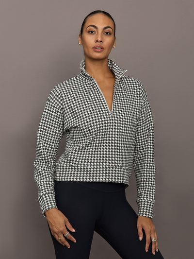 Model wearing houndstooth half-zip pullover with high collar, front view.