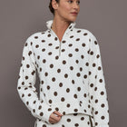 Model is wearing the Polka Dot Half Zip in white with carafe polka dot print shown from the front with cropped relaxed fit.