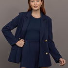 Model wears the Navy double-breasted blazer in Scuba, with a tailored fit, and a smooth, contoured finish.