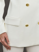 Model wears the white double-breasted blazer in Scuba, with a tailored fit, and a smooth, contoured finish.