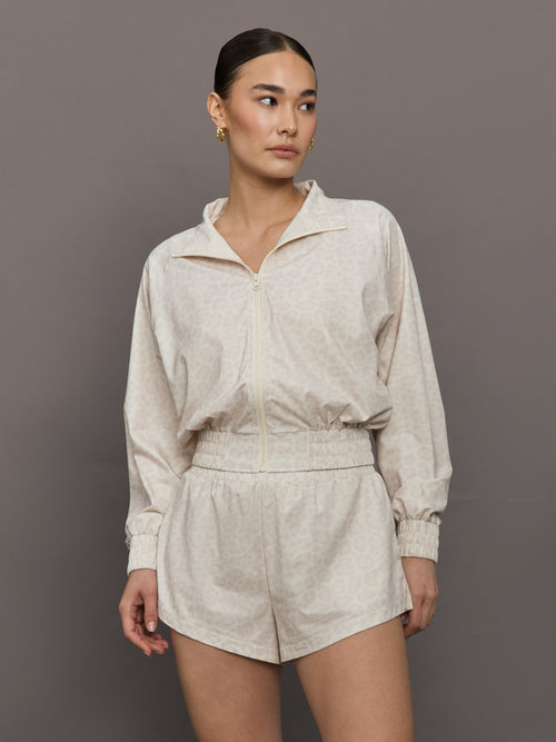 Model wears lightweight windbreaker with a snow leopard print, front zipper, and collared neck.




