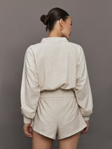 Model wears lightweight windbreaker with a snow leopard print, front zipper, and collared neck.
