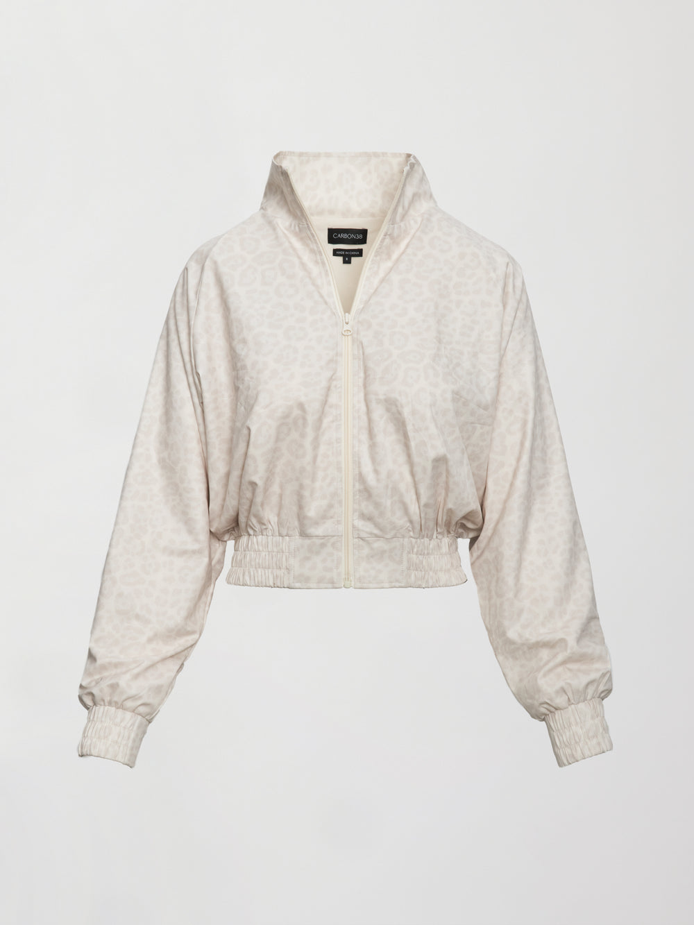 Model wears lightweight windbreaker with a snow leopard print, front zipper, and collared neck.
