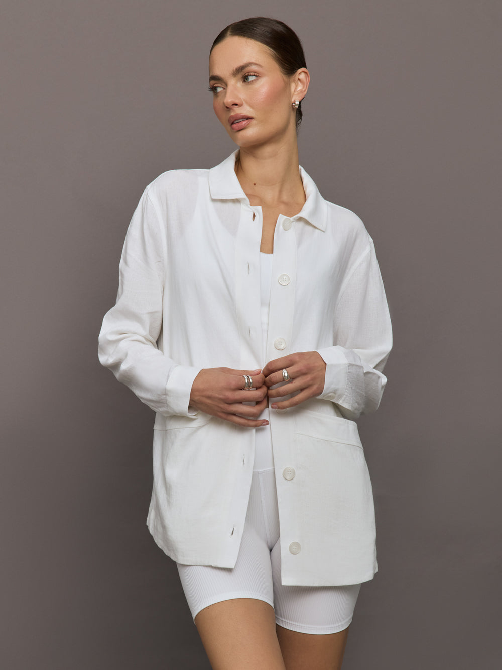 Model wears white collared linen jacket with buttons down the front and long sleeves.





