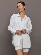 Model wears white collared linen jacket with buttons down the front and long sleeves.





