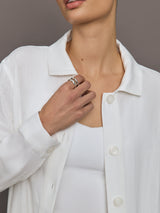 Model wears white collared linen jacket with buttons down the front and long sleeves.
