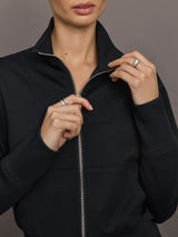 Model wears black Interlock Full Zip Jacket featuring a sleek, minimalist design with a high collar and full-length zipper.