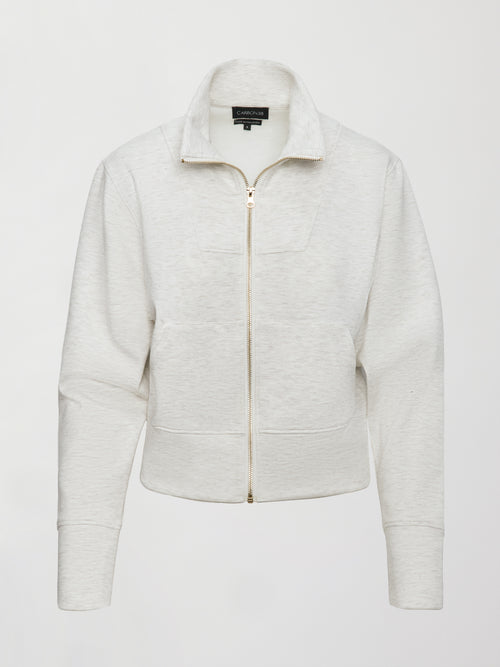 Model wears ivory Interlock Full Zip Jacket featuring a sleek, minimalist design with a high collar and full-length zipper.