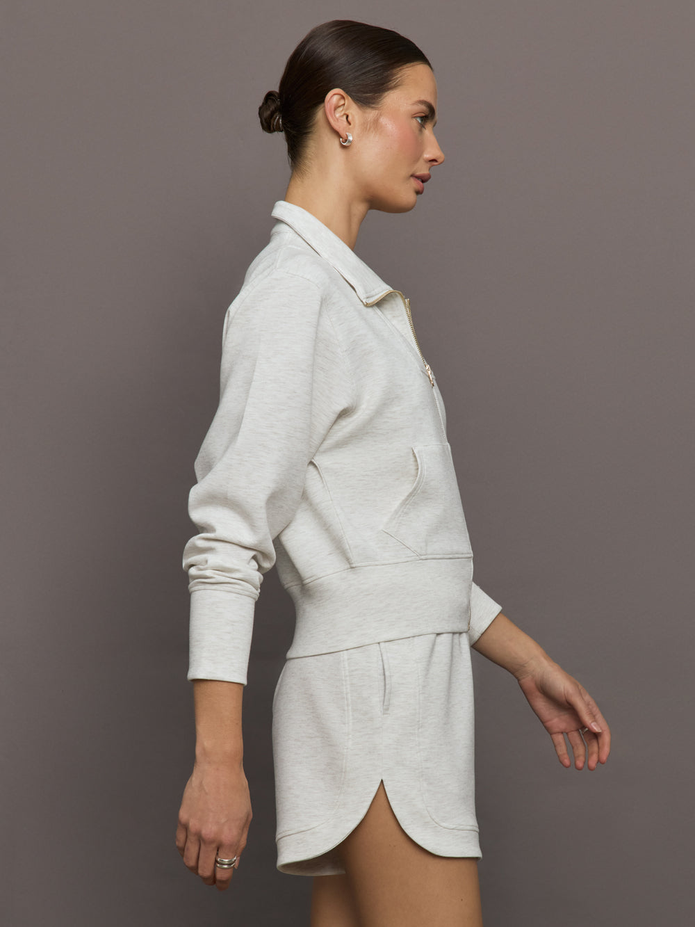 Model wears ivory Interlock Full Zip Jacket featuring a sleek, minimalist design with a high collar and full-length zipper.