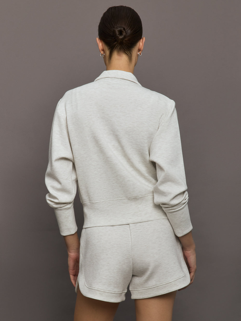 Model wears ivory Interlock Full Zip Jacket featuring a sleek, minimalist design with a high collar and full-length zipper.