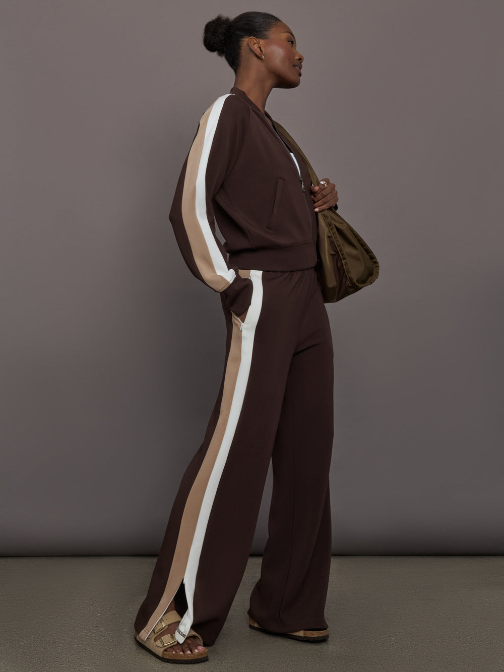 Model wearing brown bomber with white and beige stripes on the sleeves.