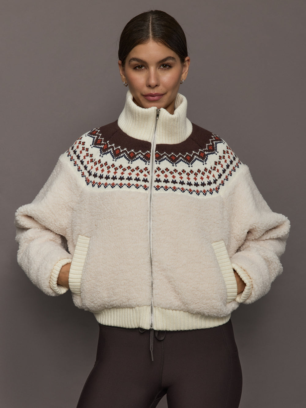 Model wearing Fairisle Sherpa Jacket in natural nude sherpa with multicolor Fairisle knit yoke and zip front, front view.