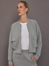 Model is wearing a heather grey Ultrasoft Bomber Jacket with front zip closure and utility pockets, front view.