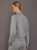 Model is wearing a heather grey Ultrasoft Bomber Jacket with clean straight hem and raglan sleeve construction, back view.