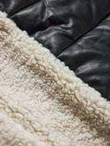 Close up view of natural sherpa fleece with smooth black faux leather contrast.