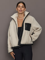 Model is wearing sherpa jacket in natural with exposed faux leather lining, open zip styling.