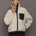 Model wearing Faux Leather Sherpa Jacket in natural sherpa with black faux leather trim and chest pocket, front view.