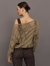 Model wears a crocheted one shoulder sweater in light brown.