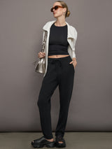 Model wears a short sleeved, ribbed jersey fitted black top with ruching down both sides. 