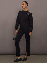 Full outfit view of black martini embellished sweatshirt styled with black split-hem pants, loafers, and mini handbag.
