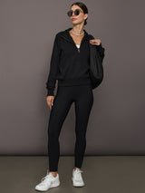 Model is wearing the Half Zip Fleece Top in black styled with black leggings, white sneakers, oversized black shoulder bag, and sunglasses, full front view.