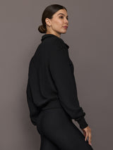 Model is wearing the Half Zip Fleece Top in black with ribbed hem and relaxed fit, back side view.