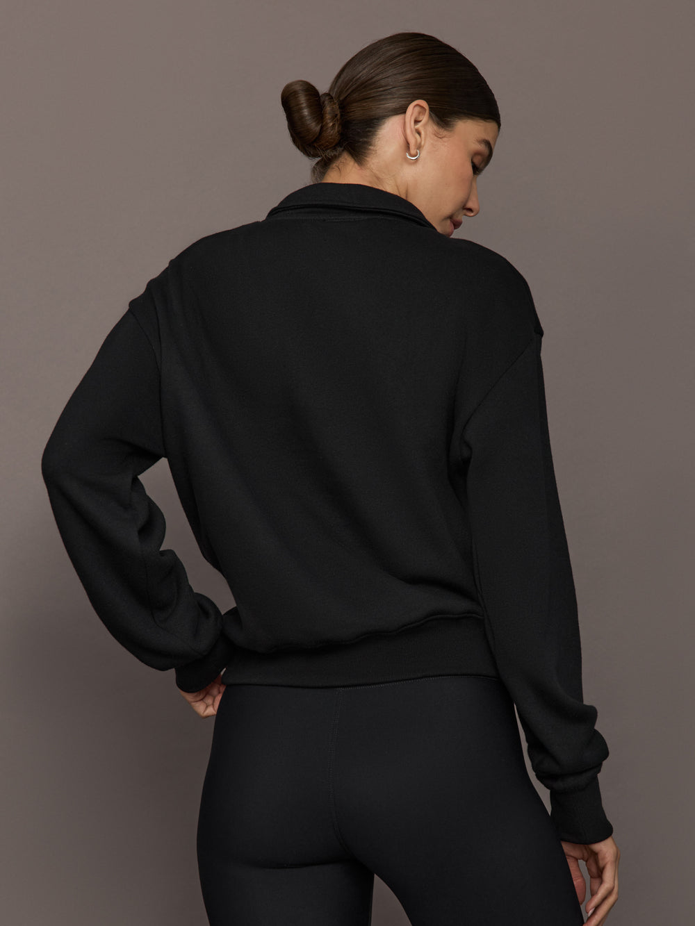 Model is wearing the Half Zip Fleece Top in black with dropped shoulders and ribbed hem, back view.
