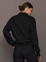 Model is wearing the Half Zip Fleece Top in black with dropped shoulders and ribbed hem, back view.
