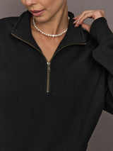 Close-up of the Half Zip Fleece Top in black showing gold zipper and stand collar detail.