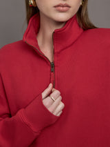 Model wears a fire engine red long sleeve half zip sweatshirt. 