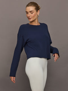 Side view of model wearing French Terry Crew Neck Sweatshirt in Navy Blazer with white leggings.