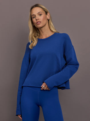 Model is wearing French terry crew neck sweatshirt in cobalt, front view.