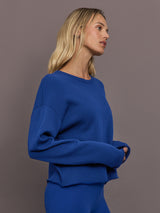 Model is wearing French terry crew neck sweatshirt in cobalt, side view.