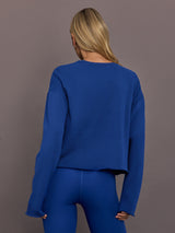 Model is wearing French terry crew neck sweatshirt in cobalt, back view.