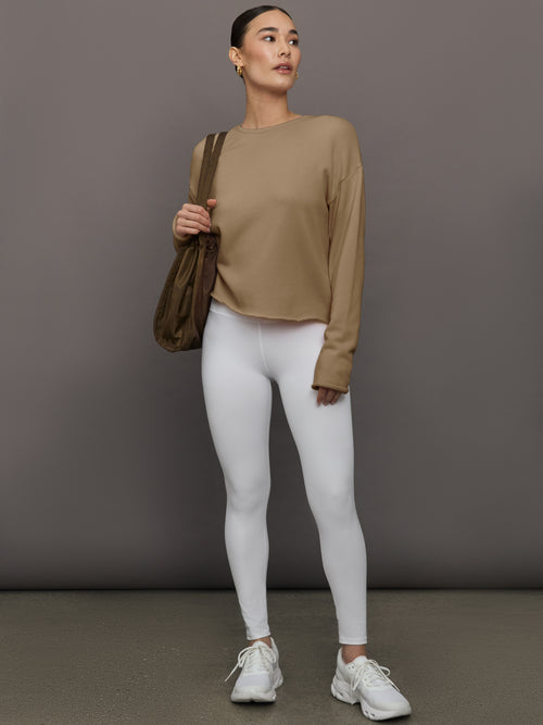 Full body view of model in Crew Neck Sweatshirt in French Terry Chinchilla styled with white leggings and sneakers.