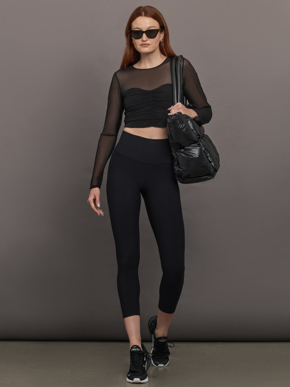 Model wears the The Melt and Mesh Ruched Top in Black, with a ruched center front, mesh on the sleeves and upper chest, and is cropped.