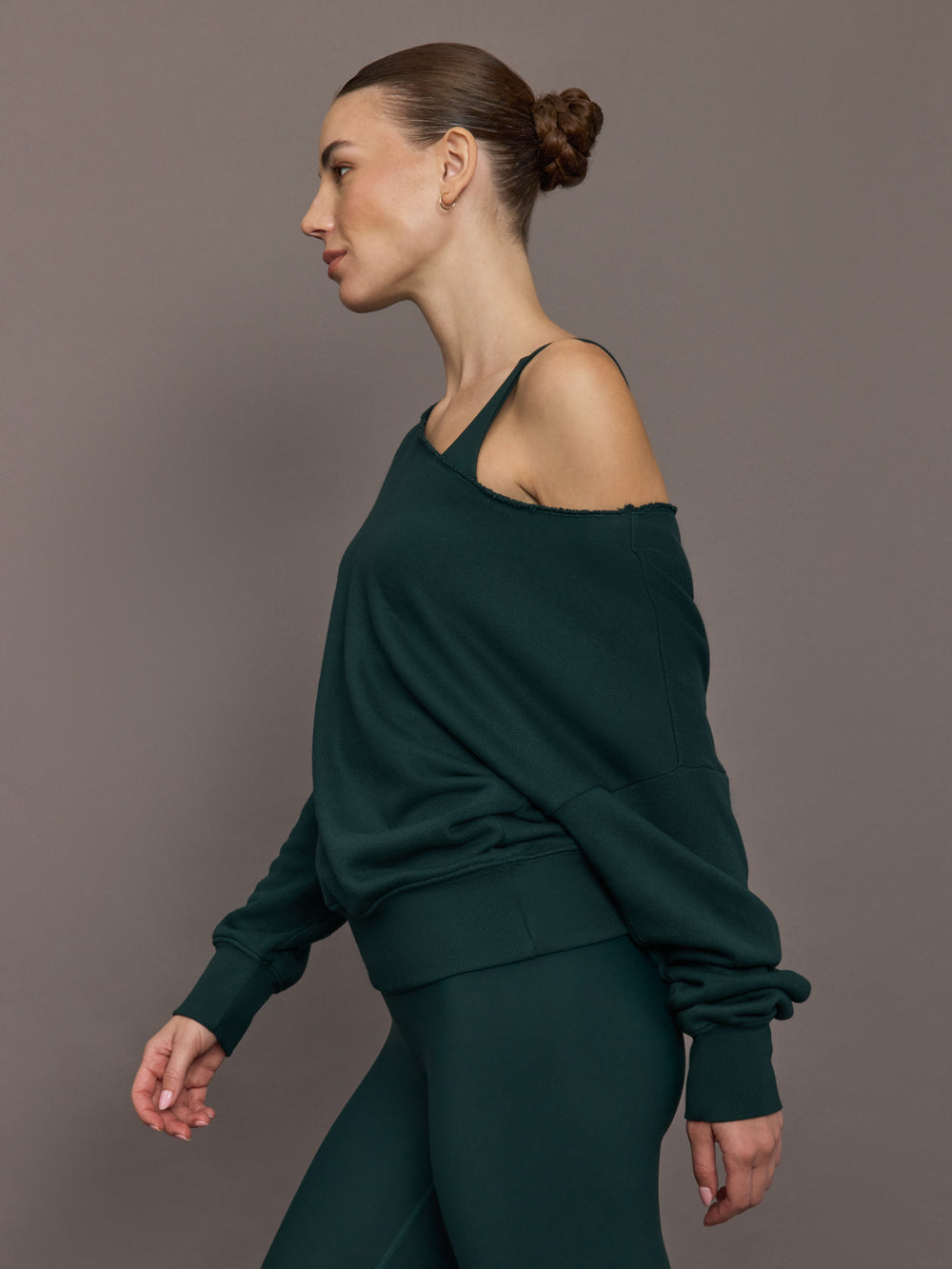 Model is wearing the Off Shoulder Sweatshirt in Forest, side profile.