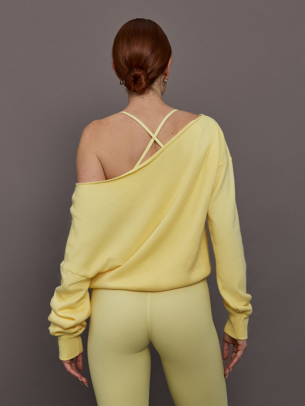 Model is wearing the French Terry Off-Shoulder Sweatshirt in Banana, back view highlighting the wide neckline.