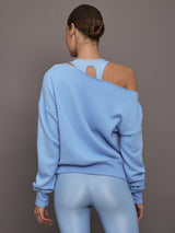 Model is wearing the Off Shoulder Sweatshirt in French Terry in Serenity shown from the back revealing layered sports bra detail.