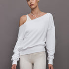 Model wears a white slouchy, off-the-shoulder French terry sweatshirt with a raw-edged asymmetrical neckline and a relaxed, roomy fit.




