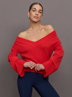 Model wears red off-shoulder sweater with bell sleeve.
