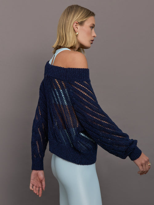 Model wears a navy off shoulder mesh cardigan with diagonal pattern.  