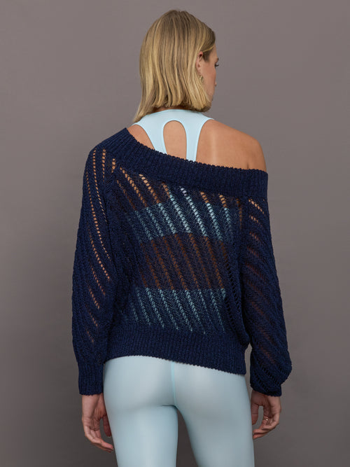 Model wears a navy off shoulder mesh cardigan with diagonal pattern.  
