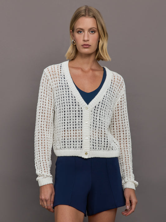 Model wears an open knit, v neck button down white cardigan. 