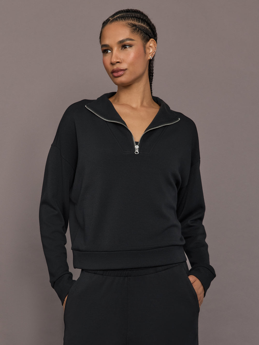 Model is wearing Interlock half zip pullover in black, close-up front view.