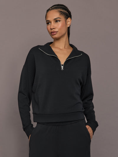 Model is wearing Interlock half zip pullover in black, close-up front view.