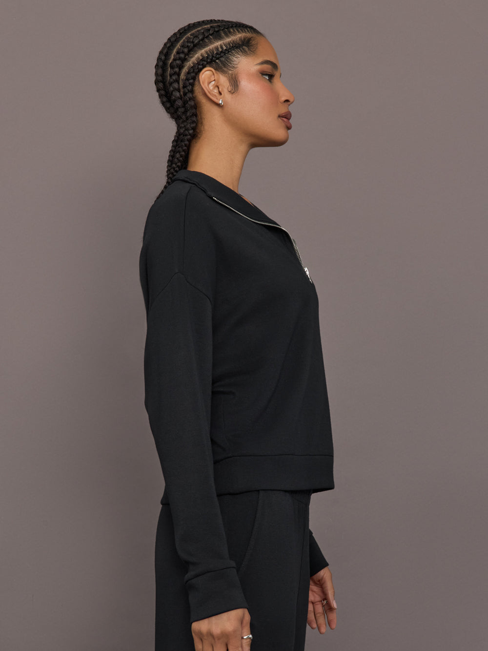 Model is wearing Interlock half zip pullover in black, side profile view.