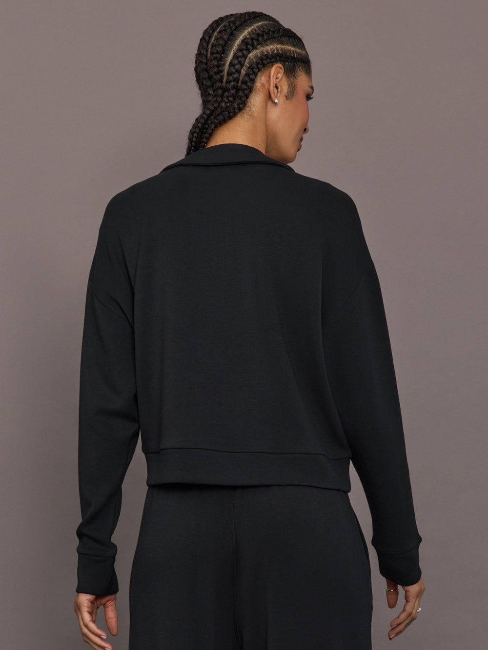 Model is wearing Interlock half zip pullover in black, back view.