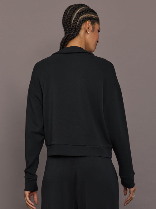 Model is wearing Interlock half zip pullover in black, back view.
