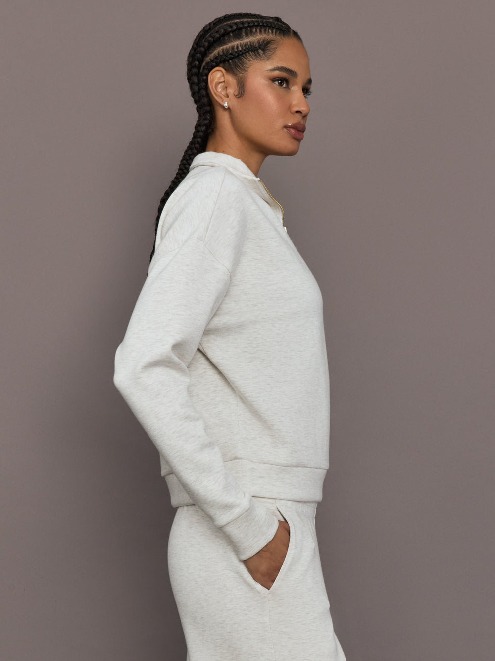 Model is wearing Interlock half zip pullover in Moonbeam Heather, side profile view.